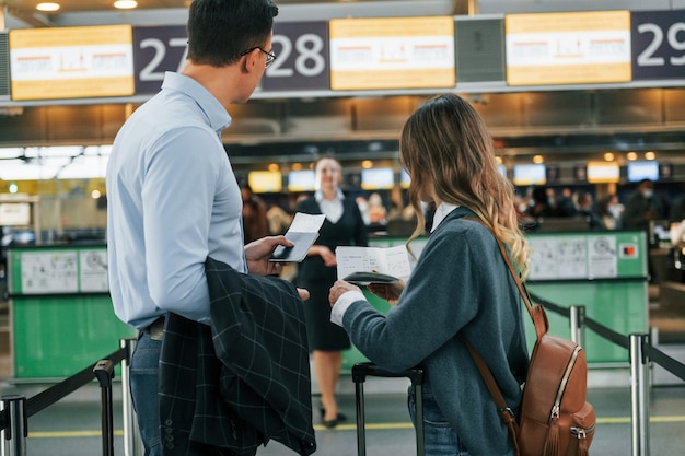 Travelers at airport check-in for Air New Zealand flights during rising ticket prices.