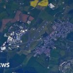 Astronaut taking a photo of a university from space, showcasing the campus layout.