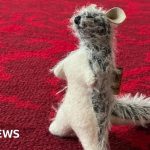 A woman in professional clothing stands among the Winnie-the-Pooh collection.