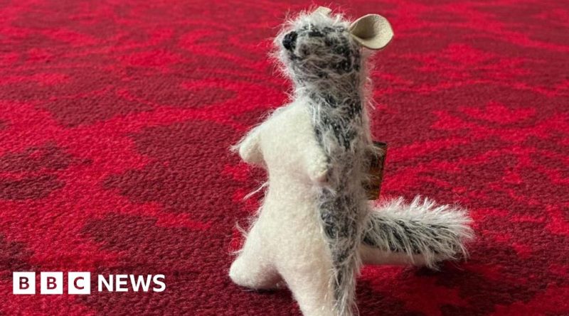 A woman in professional clothing stands among the Winnie-the-Pooh collection.
