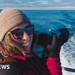 Choir members singing with whale sounds in a coastal setting.