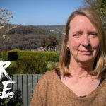 Professionals discussing wind farms in Wales amidst green hills.