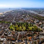 A meeting discussing debt struggles in a coastal town, with professionals in business attire.