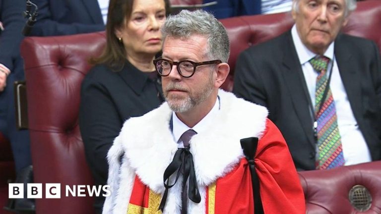 A serious discussion about a Starmer aide's diplomatic role among professionals in a modern office.