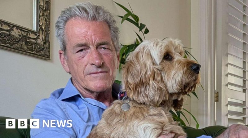 A dog walker in professional attire stands in a park with dogs, reflecting on the recent attack he endured.