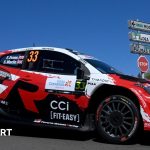 Rally drivers strategizing in the paddock during the World Rally Championship.