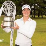 Esme Hamilton celebrating her European Tour victory with a trophy on the golf course.