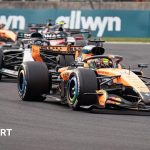 Engine engineers analyzing new F1 engine regulations in a workshop.