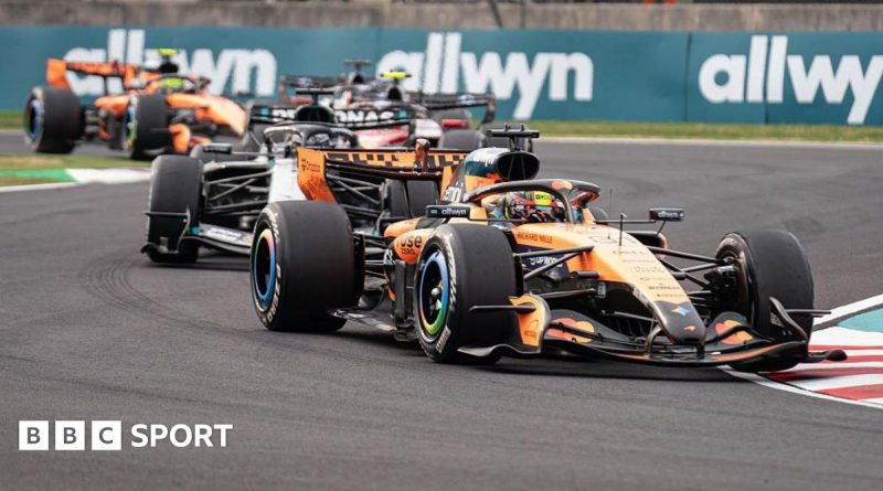 Engine engineers analyzing new F1 engine regulations in a workshop.