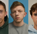 A concerned family member stands near a damaged house after an arson attack.