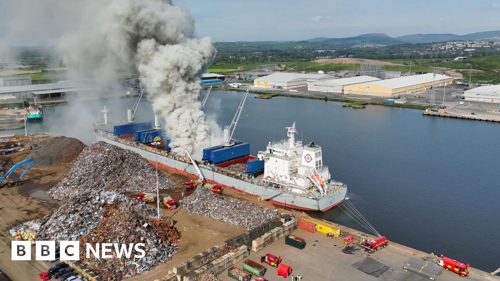 Firefighters tackling a fire on a cargo ship carrying scrap metal.