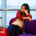 Diverse business travelers at an airport check-in area regarding flight cancellations to the UK.
