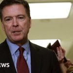 Professionals discussing Comey charges related to Trump threat in a meeting.