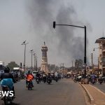 Professionals discussing safety in Mali amidst rising violence threats.