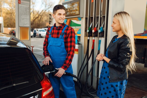 People in professional attire at a gas station as fuel prices increase.