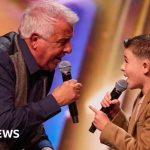 Grandfather and grandson performing together on stage during a talent show.
