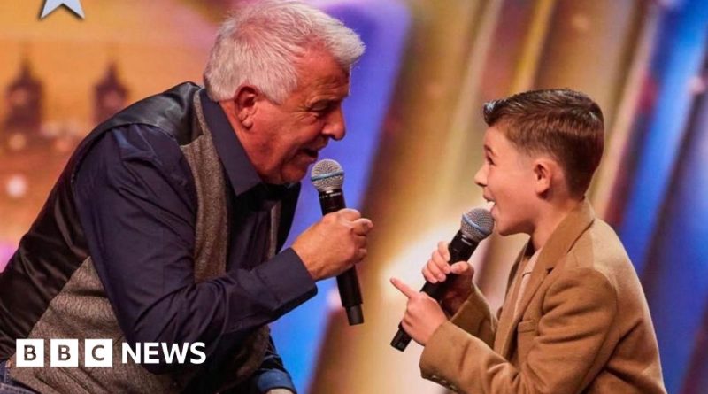Grandfather and grandson performing together on stage during a talent show.