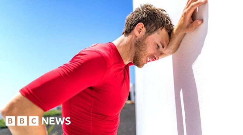 Professionals assisting a person with heat exhaustion symptoms outdoors.