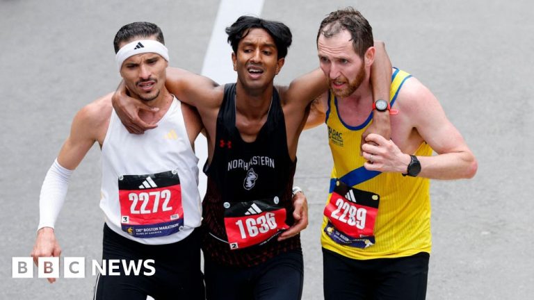 Runners help exhausted man cross marathon finish line, showing teamwork.