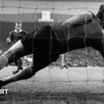 Tense scene of the first penalty shootout in football, showcasing players and crowd excitement.