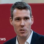 A diverse group in a meeting discussing leasehold reform in professional attire.