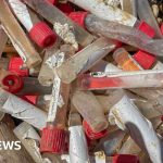 People discussing medical waste on Sheppey beach in professional attire.