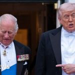 Politicians discussing the King's US visit impact in a banquet hall.