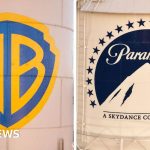 Professionals discussing the Paramount Warner Bros acquisition in a meeting.