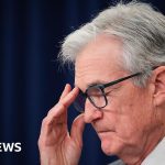 A diverse group of professionals discussing economic issues at a conference, highlighting Jerome Powell press conference.