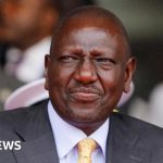 Diverse professionals in formal attire discussing Kenyan President comments.