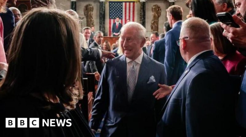 A diverse group of professionals in formal attire listening to a speech about US-UK partnership.