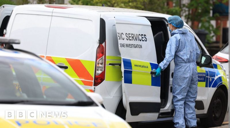 Police officers discussing the London arson investigation in a busy street.