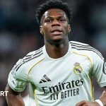 Football analysts discussing Aurelien Tchouameni transfer news in a modern office.