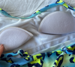 Parents looking at children's clothing in a charity store, addressing inappropriate children's swimwear.