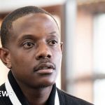 Business professionals discussing Mugabe's son deportation case in a serious meeting.