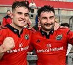 Munster vs Ulster rugby match showing players in action and a cheering crowd.