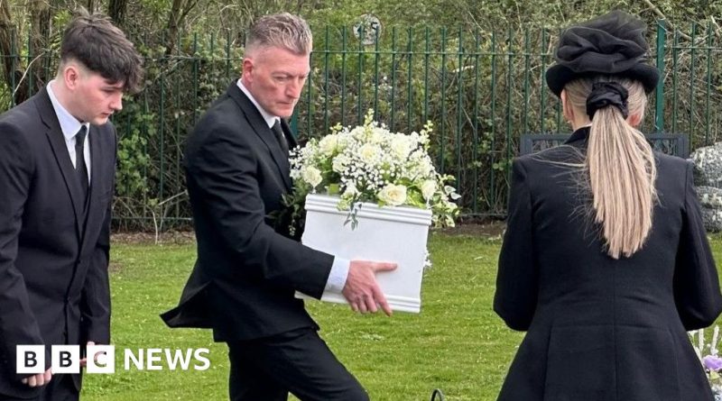Community members gather for a mystery baby burial ceremony.