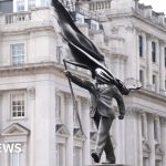 A crowd admires a Banksy-style sculpture in a London park.