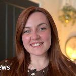 A woman in professional attire worried about NHS waiting lists.