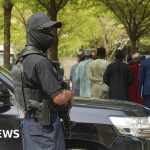 Professionals discussing Nigeria coup investigation in an office setting.