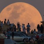 A group of people in professional attire observing the November supermoon.