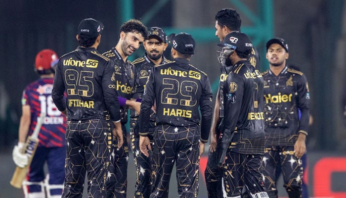 Peshawar Zalmi players celebrate during a PSL match in a stadium.