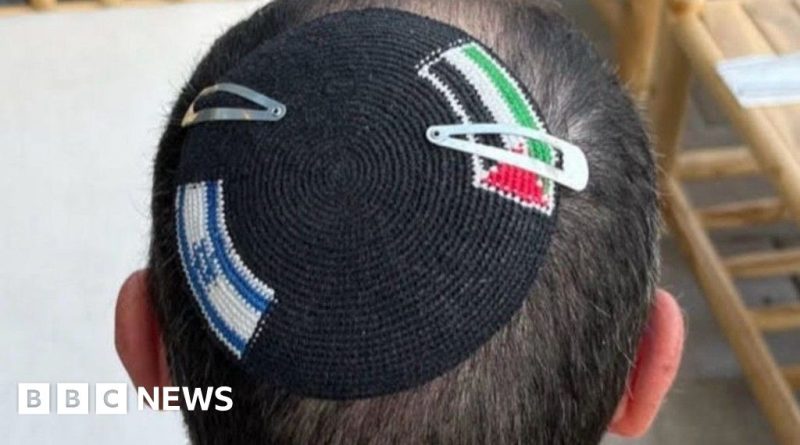 A diverse group discussing the Palestinian flag kippah incident in a public area.