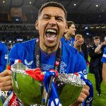 Rangers FC captain Tavernier with teammates on the pitch, celebrating teamwork.