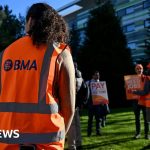 Resident doctors in England discussing their pay dispute in a hospital.