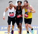 Runners showing support for a competitor at the Boston Marathon finish line.