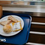 Teachers preparing a free breakfast program in a school cafeteria.