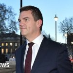 A professional group discussing a vetting controversy in a well-lit office.