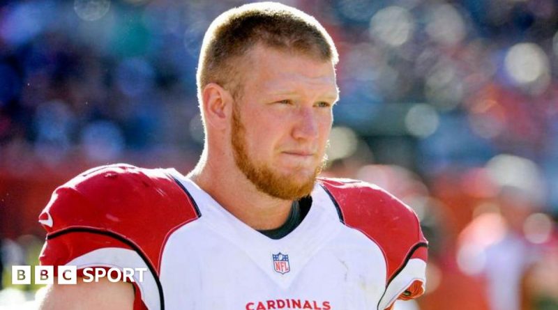 A memorial for Josh Mauro with flowers and jerseys at a football field.
