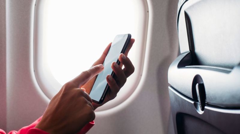 Business professionals in an airplane with airplane mode activated on devices.